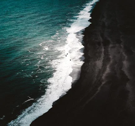 Le contraste saisissant de l'océan Atlantique et du sable noir de Reynisfjara en Islande