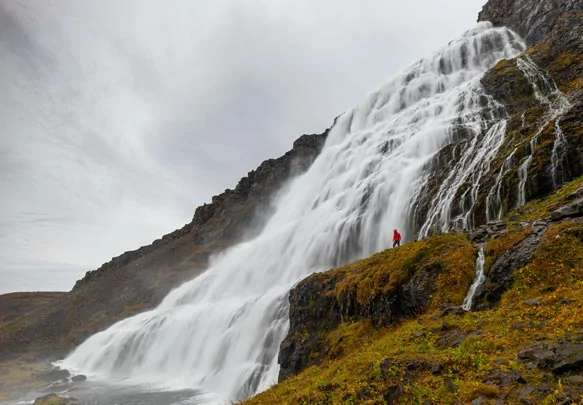 Un touriste au plus près de la cascade Dynjandidans les fjords de l'Ouest islandais