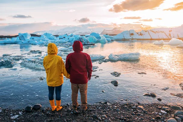 Un couple de touriste admirant les icebergs flottants du Jokulsarlon en Islande