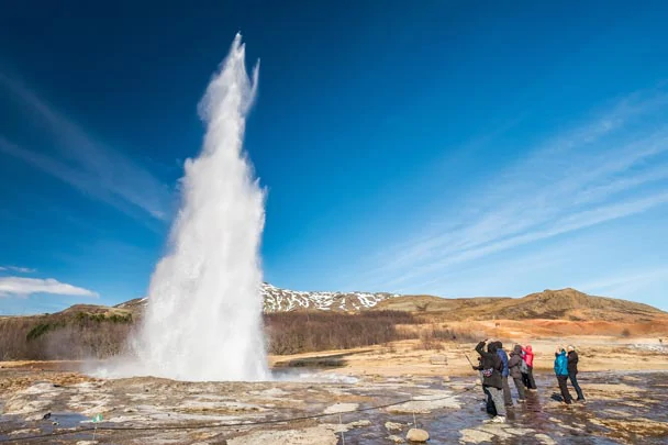 Des touristes photographiant l'éruption du Strokkur en Islande