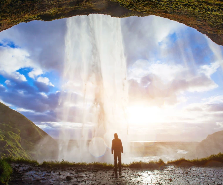 Un touriste derrière les eaux de la chute de Seljalandsfoss